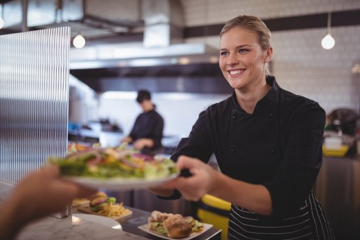 photo kitchen staff serving food on plate to customer