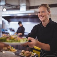 photo kitchen staff serving food on plate to customer